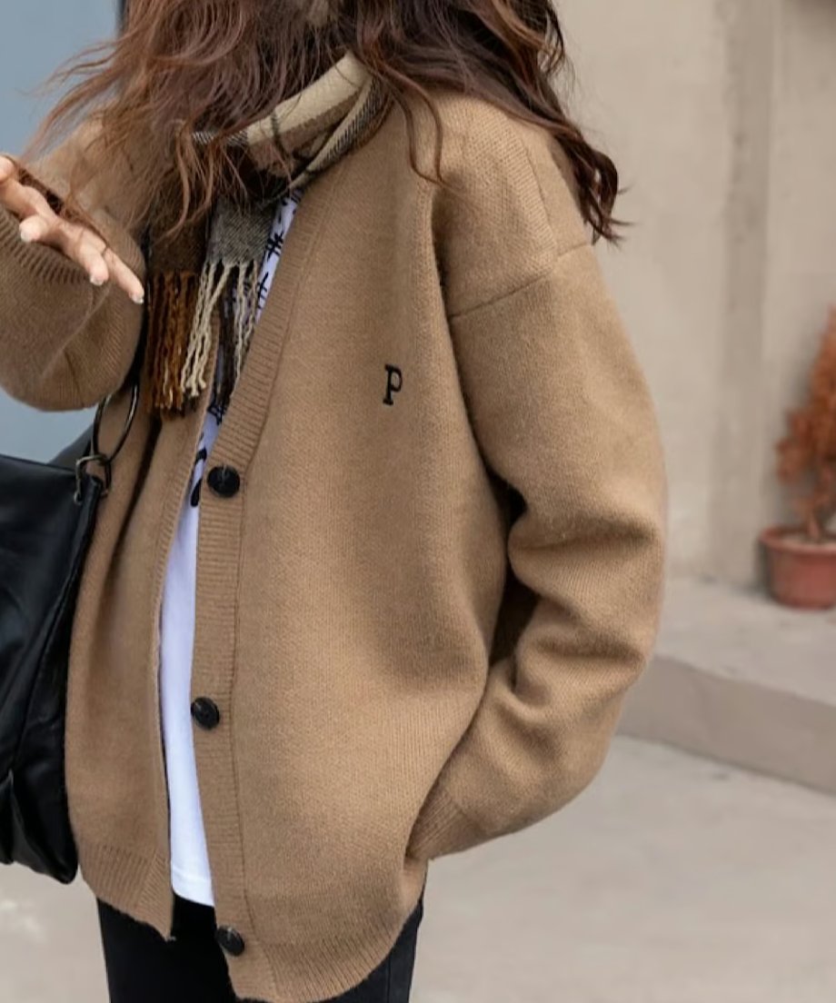 キャメルのオーバーサイズカーディガンと白いTシャツにチェック柄マフラーを合わせた女性の上半身。