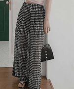 ハイウエストドット柄パンツに黒のハンドバッグを合わせた、モノトーンでまとめたスタイリッシュな装い。