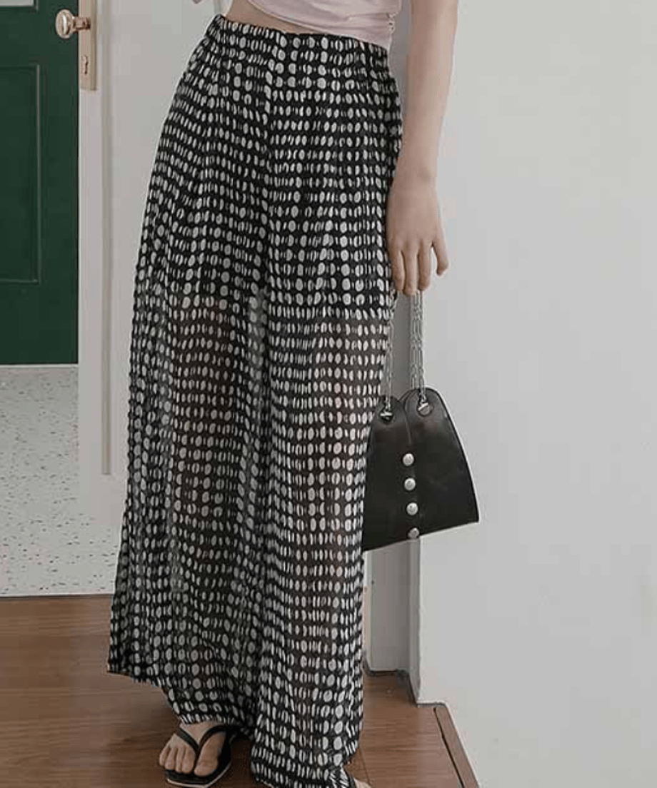 ハイウエストドット柄パンツに黒のハンドバッグを合わせた、モノトーンでまとめたスタイリッシュな装い。