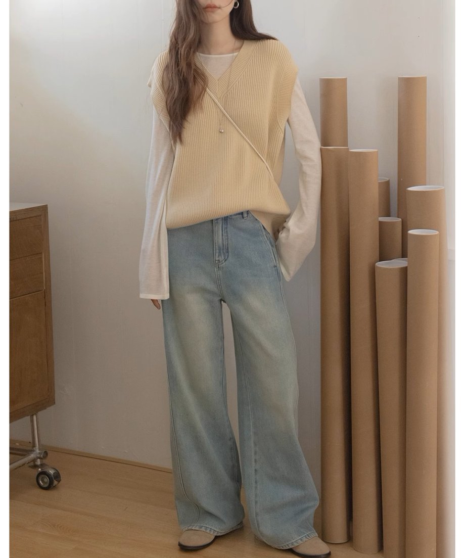  ベージュのリラックスフィットニットベストを着用した女性。デニムパンツと合わせたカジュアルスタイル。