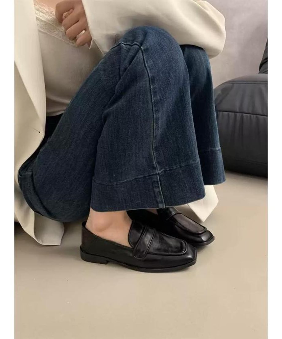 ブラックの合皮製スクエアトゥローファーを履いた女性が座っている写真。