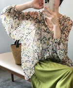 花柄のゆったりとしたブラウスと緑色のプリーツスカートのクローズアップ。 横に置かれたかごバッグ。