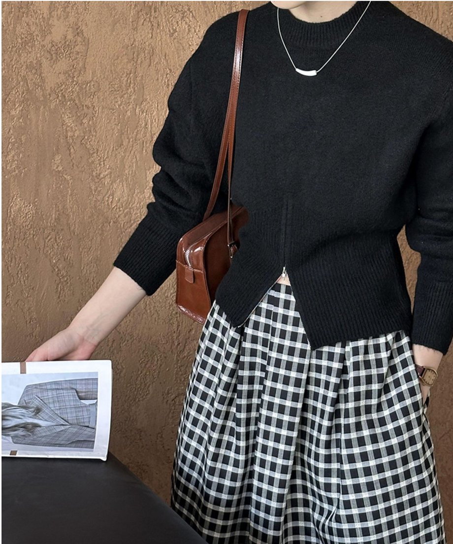 ブラックのハーフジップニットと白黒チェックのロングスカートを着用した女性の胸元。茶色のバッグを肩に掛けている。