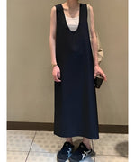 黒のロングワンピースに白いタンクトップを重ね、黒のスニーカーで引き締めたモノトーンのモードスタイル。