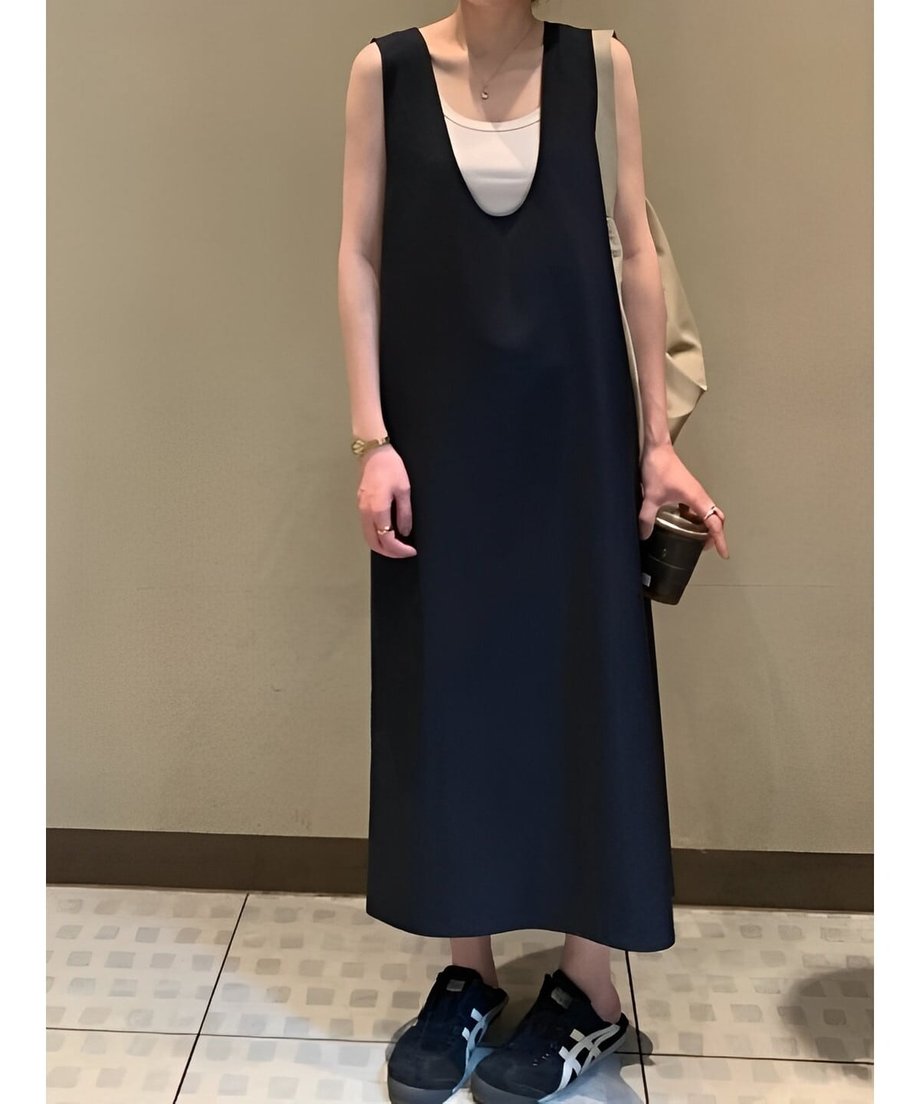 黒のロングワンピースに白いタンクトップを重ね、黒のスニーカーで引き締めたモノトーンのモードスタイル。