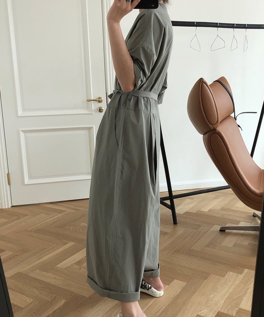 グレージュのVネックラップオールインワンを着用した女性の斜め後ろショット。