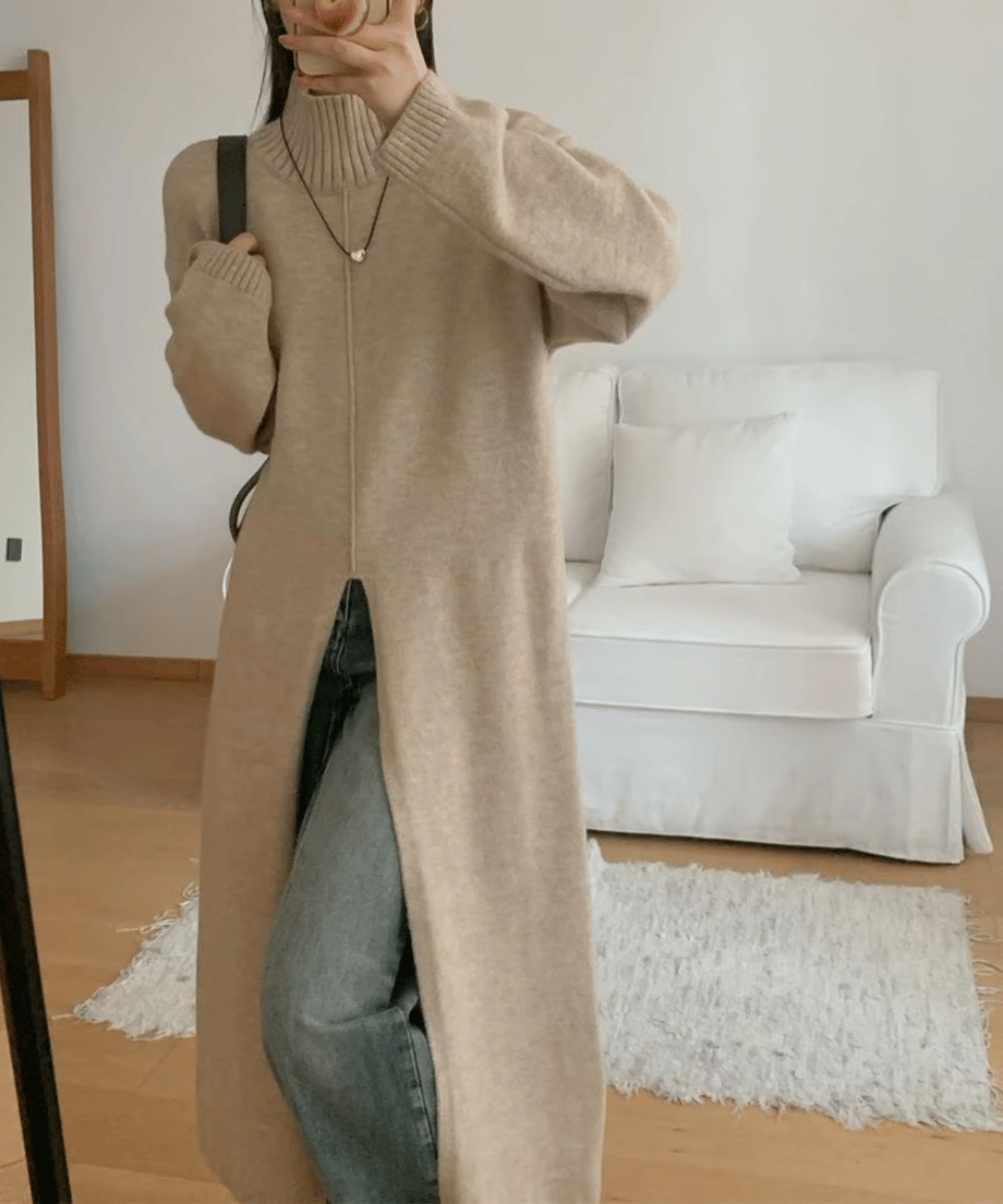 アプリコットのタートルネックロングニットを着用した女性が、インナーにデニムパンツを合わせた全身コーディネート写真。