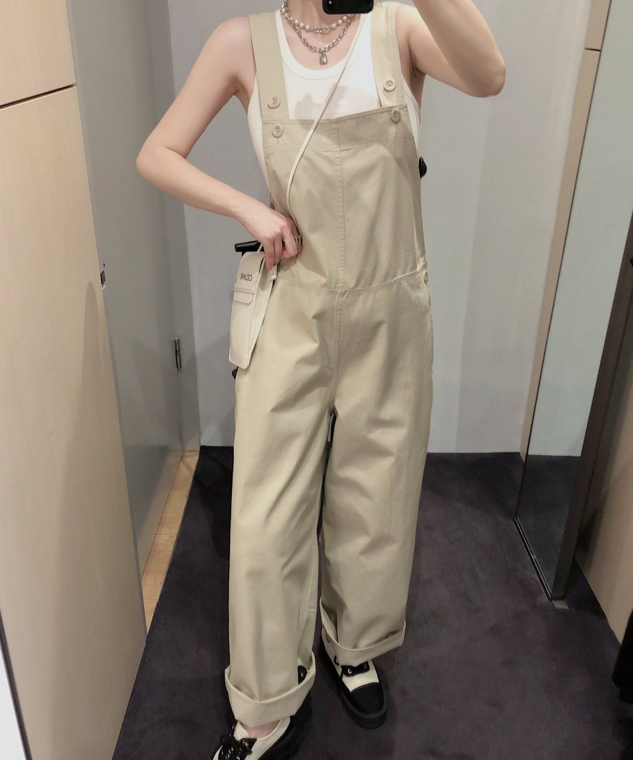 カーキのオーバーオールを着用した女性、シンプルでカジュアルな印象。
