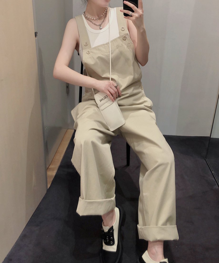 カーキのオーバーオールを着用した人物が椅子に座っている。