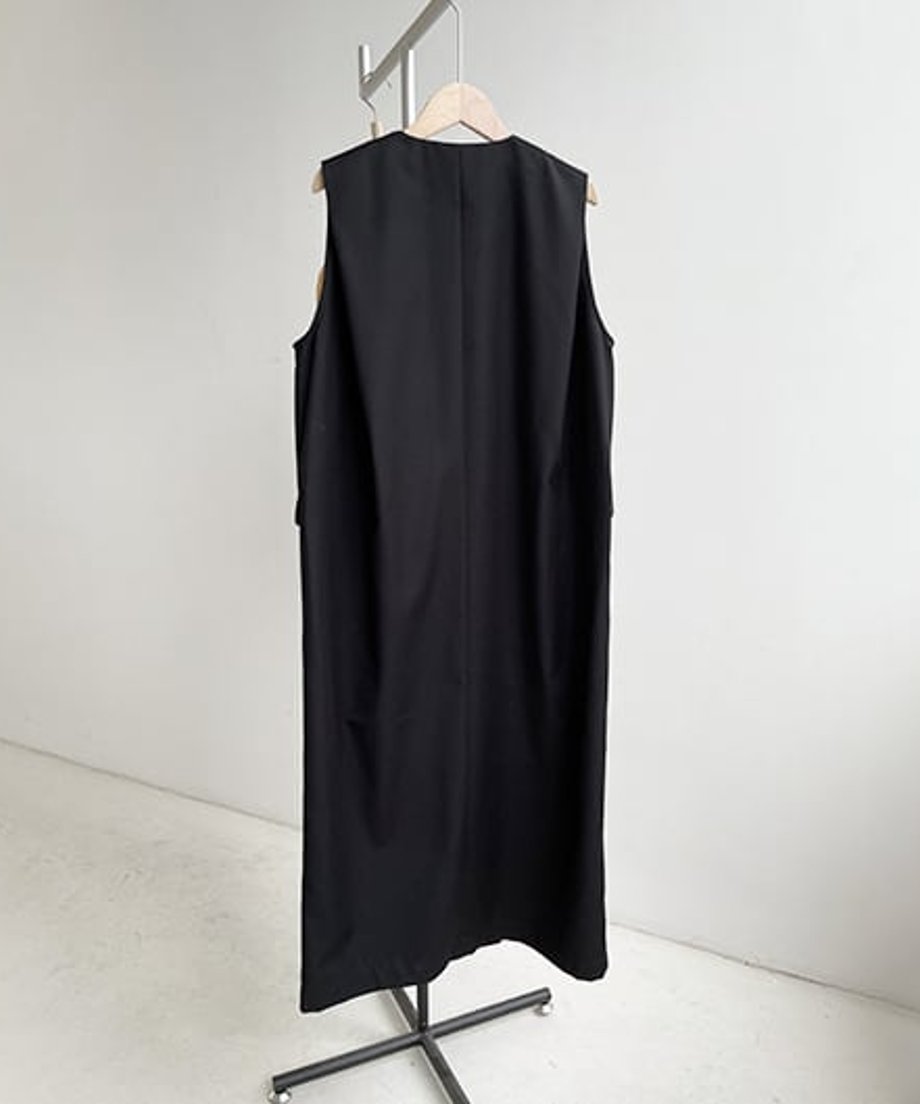 ハンガーラックにかけられた黒のロングベストの背面。シンプルなVネックとIラインのシルエット。