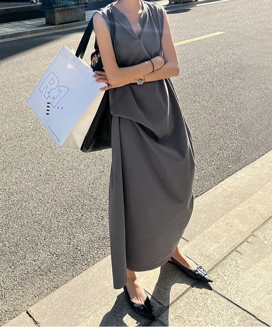 女性がチャコールグレーのワンピースを着用し、フラットシューズをあわせて街中を歩いている写真