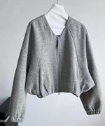 グレーのデザインジャケットのショートブルゾンの正面全体。Vネック風のノーカラーとラグランスリーブが特徴的。