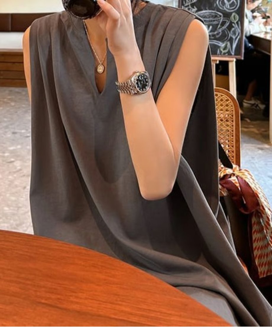 チャコールグレーのドレープワンピースを着た女性がカフェでドリンクを飲んでいる写真