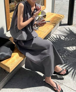 チャコールグレーのワンピースを着た女性がテーブルでドリンクを飲んでいる写真