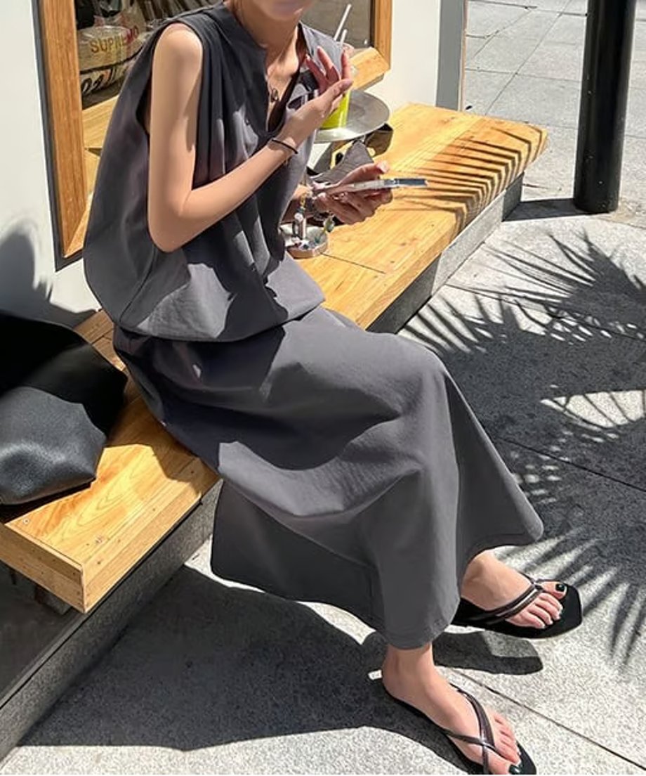 チャコールグレーのワンピースを着た女性がテーブルでドリンクを飲んでいる写真