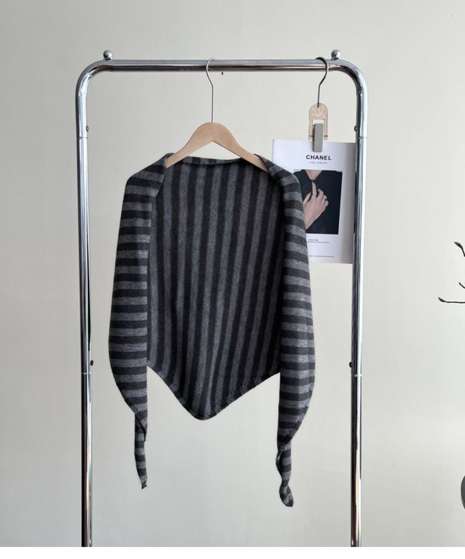 グレーストライプ柄のニットスカーフをハンガーにかけた正面の商品画像。細い部分を結んだデザインが見える。