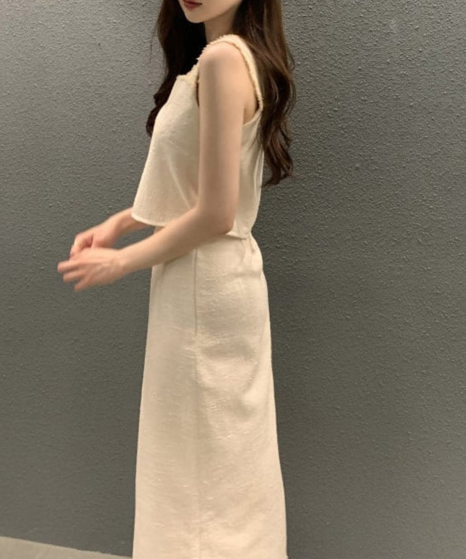 アプリコットのツイードセットアップを着用した女性の側面からの上半身の像。