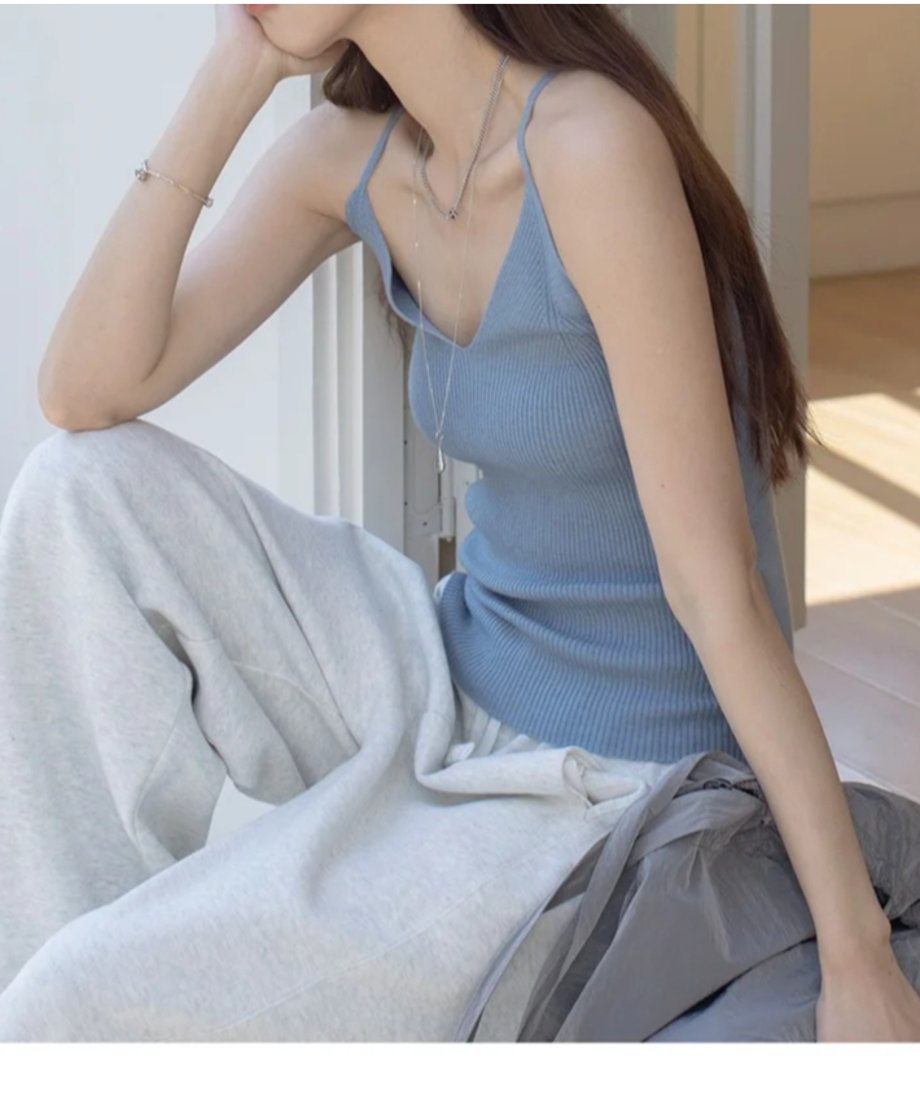 ブルーグレーのリブ編みVネックキャミソールを着用した女性。グレーのスウェットパンツと合わせた女性が座っている写真。