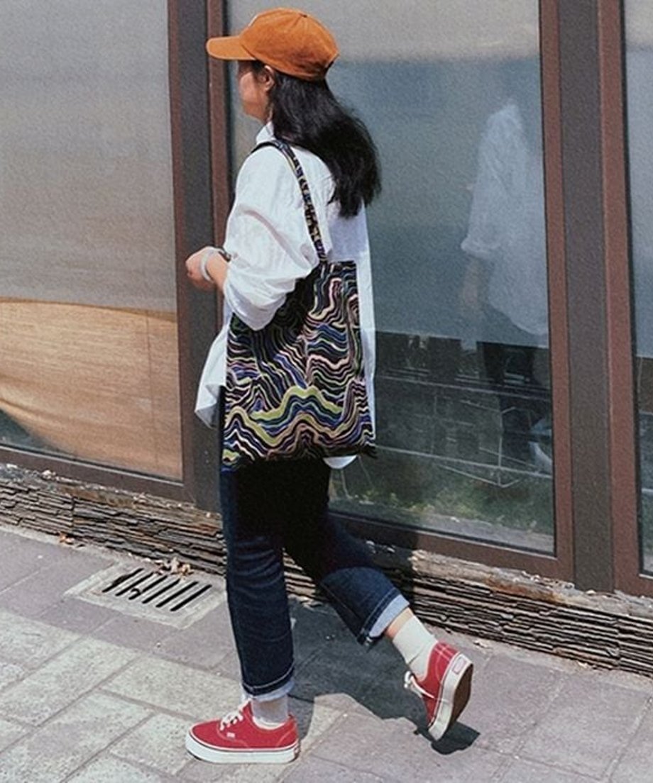 オレンジのキャップを被り、肩に掛けた柄物のバッグを肩にかけ女性のバックスタイル