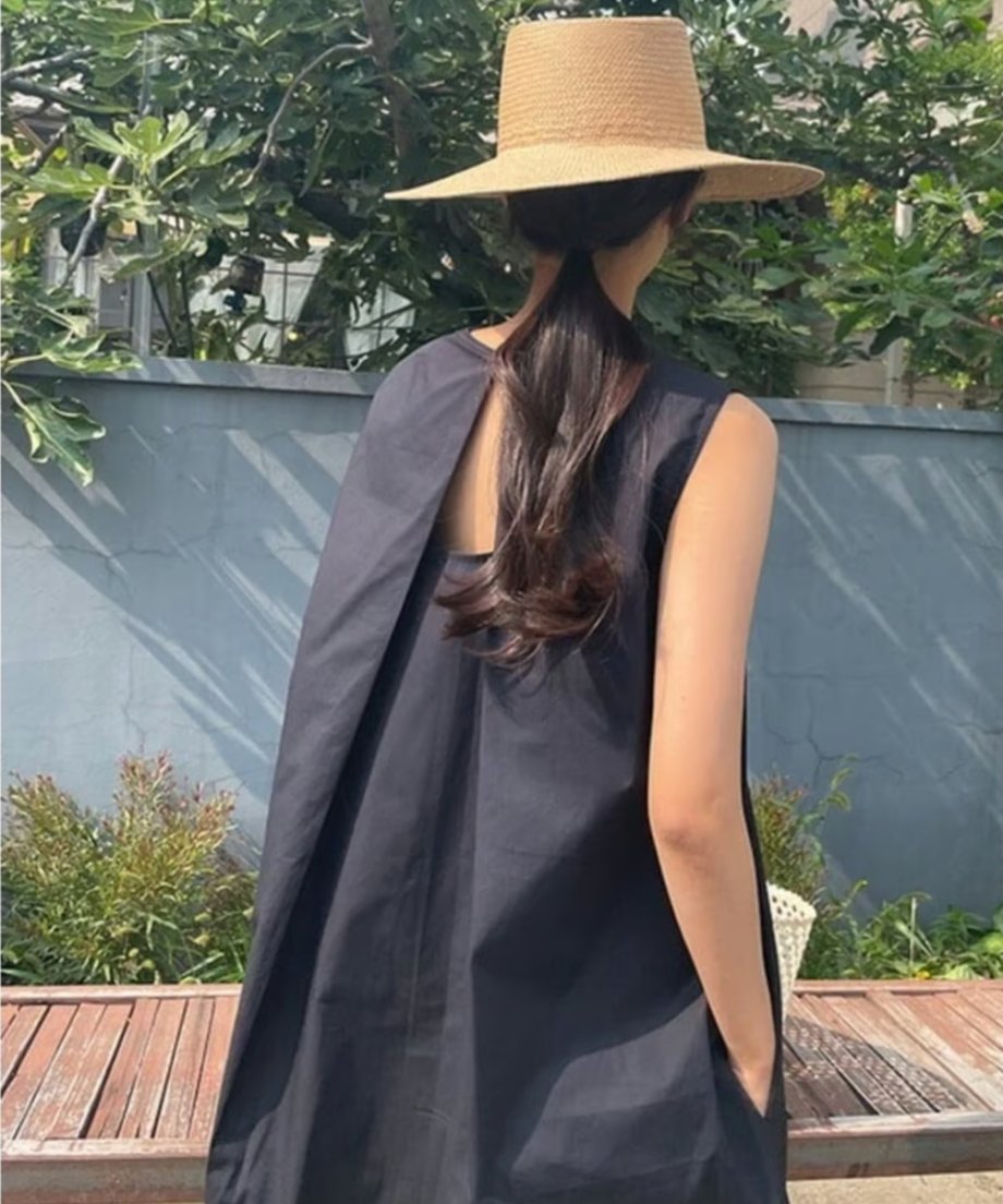黒のノースリーブマキシワンピースを着た女性の後ろ姿。背中の深いスリットが特徴。