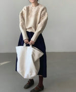 オフホワイトのフローラル刺繍セーターとネイビースカートを合わせた全身コーディネート。