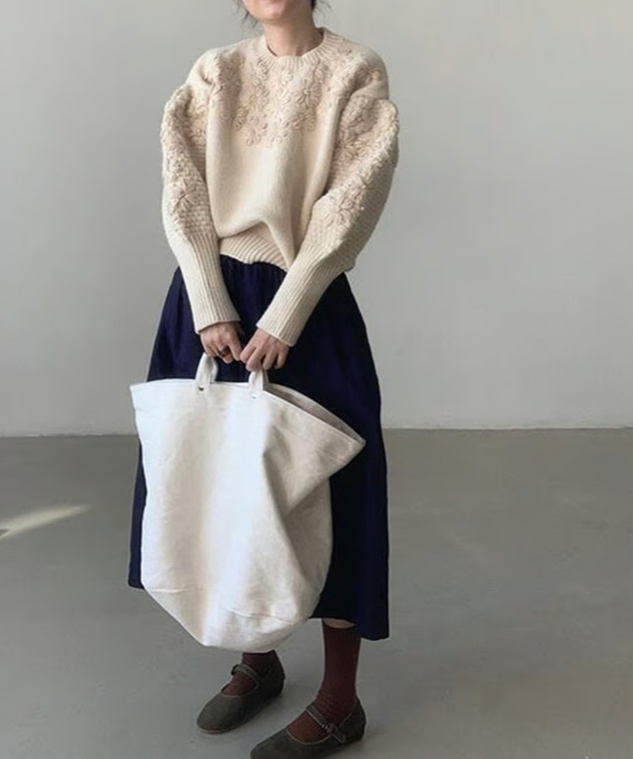 オフホワイトのフローラル刺繍セーターとネイビースカートを合わせた全身コーディネート。
