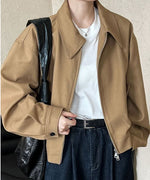 ブラウンのドロップショルダーブルゾンを着用した女性のバストアップ。インナーは白Tシャツ、ボトムスは濃紺デニム。黒いショルダーバッグを持っている。