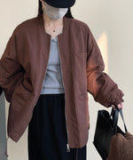 ワインのコートを着用した女性の後ろ姿。黒のキャスケットを被っている。