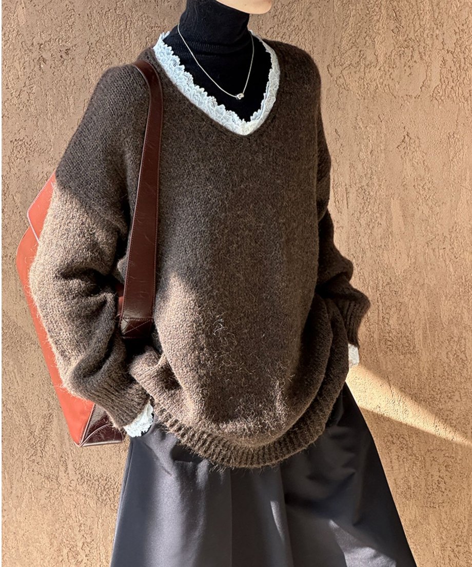 ブラウンのニットを着用した女性の全身に近い画像。黒のロングスカートと合わせ、レースの甘さを抑えた大人っぽいコーディネート。
