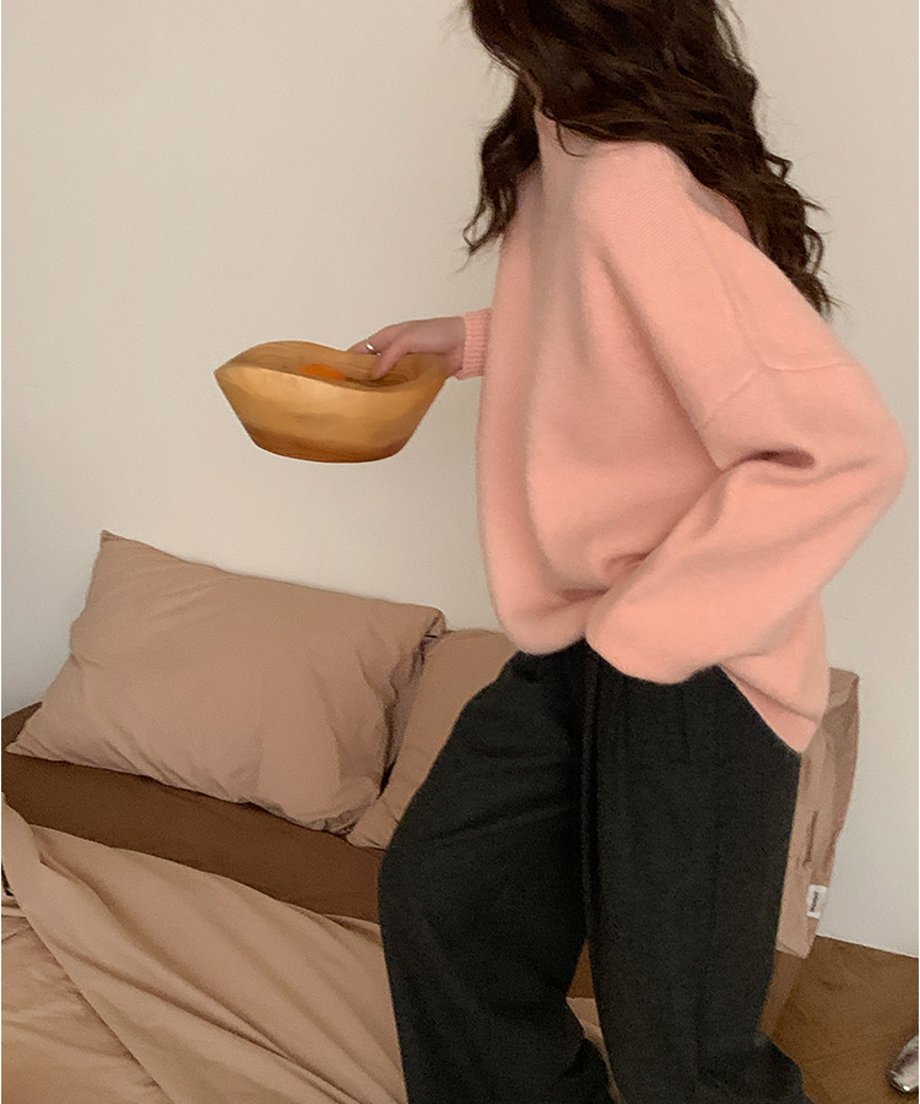 ピンクのニットトップスの生地感が分かるアップ写真。木のボウルを手に持っている。 