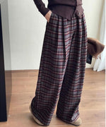 グレー・ボルドーチェックのワイドパンツとダークブラウンのカーディガンを着用し、片方のポケットに手を入れた人物のクローズアップ。