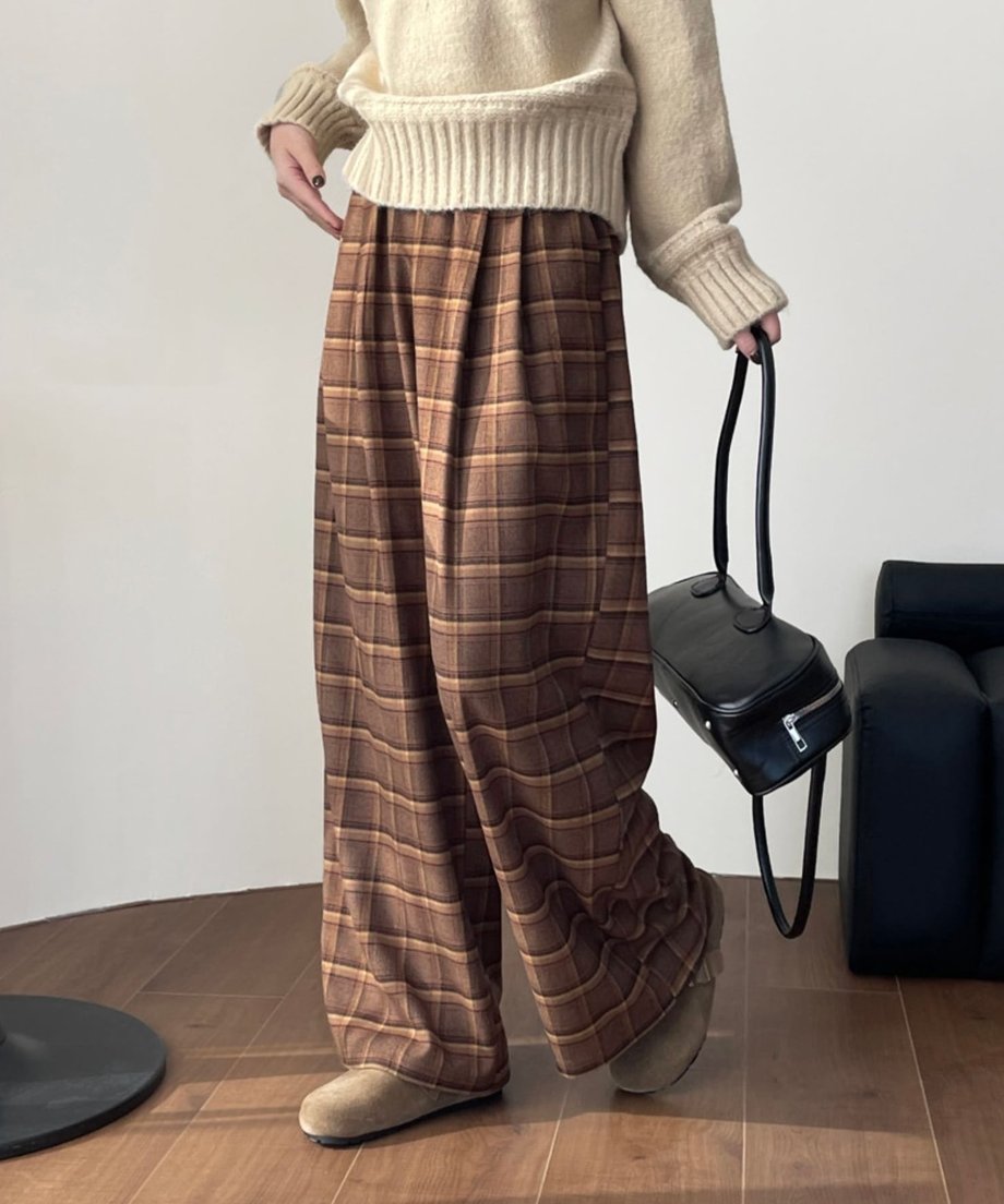 ブラウンチェックのワイドパンツとベージュのニットを着用し、立っている人物の腰から足元のクローズアップ。