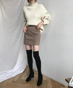 オフホワイトのタートルネックセーターを着用した全身カット。ブラウンのミニスカートと黒のソックス、ブーツをコーディネートした正面画像。
