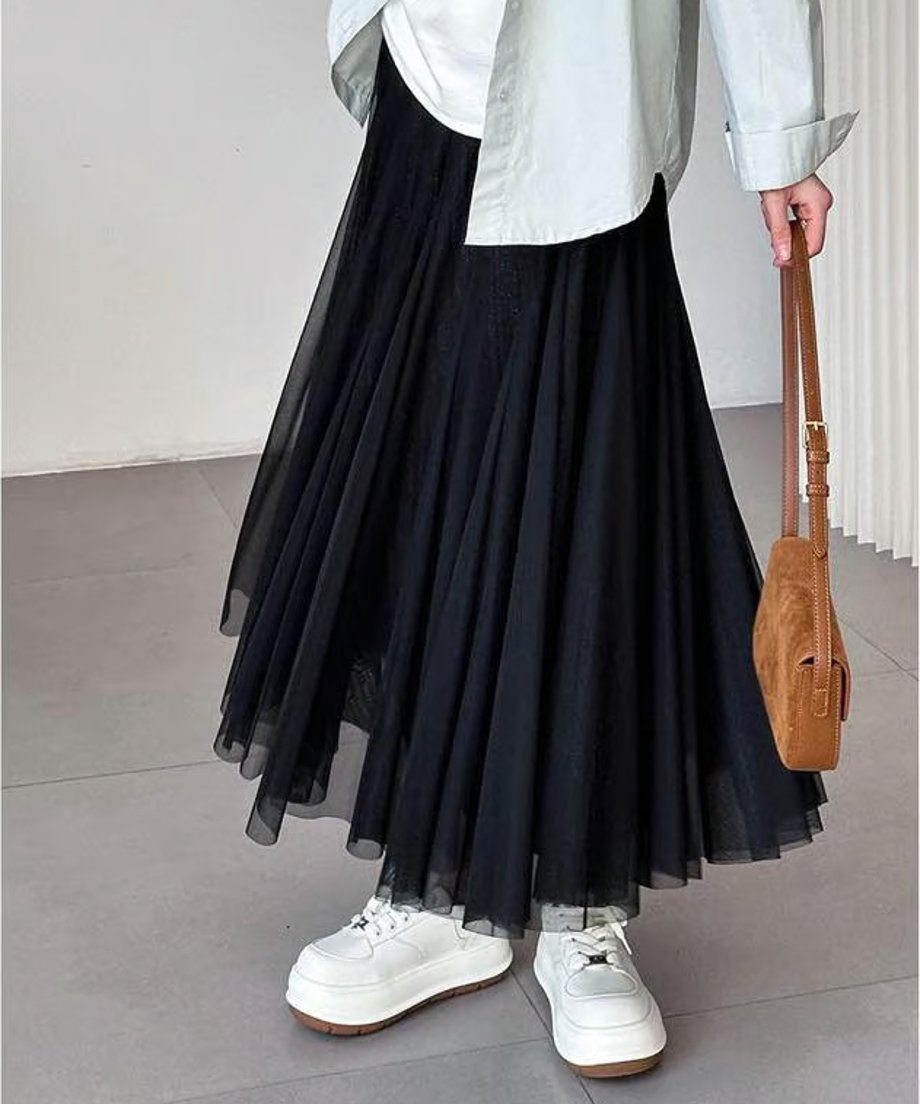 黒いチュールプリーツロングスカートを着用した女性の、膝下までのクロップショット。白に近い厚底ローファーを合わせた、モードなカジュアルスタイル。