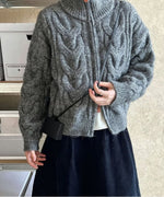 グレーのカーディガンを着用し、黒いミニバッグを斜めがけした女性の半身。スタンドカラーを少し立てた着こなし。