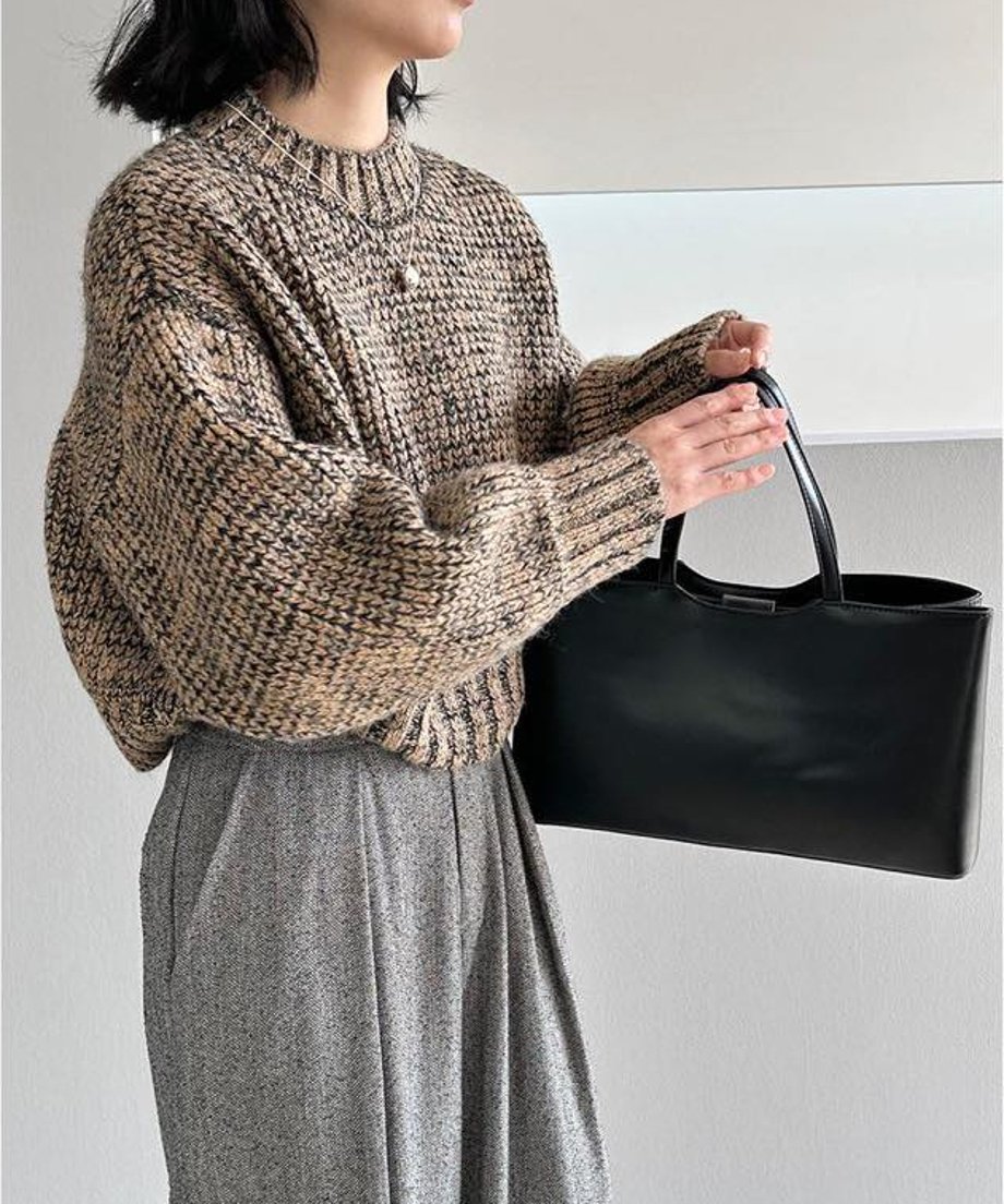 ブラウンミックスのショート丈ニットとグレーのワイドパンツを着用し、黒いバッグを持つ人物の全身ショット。