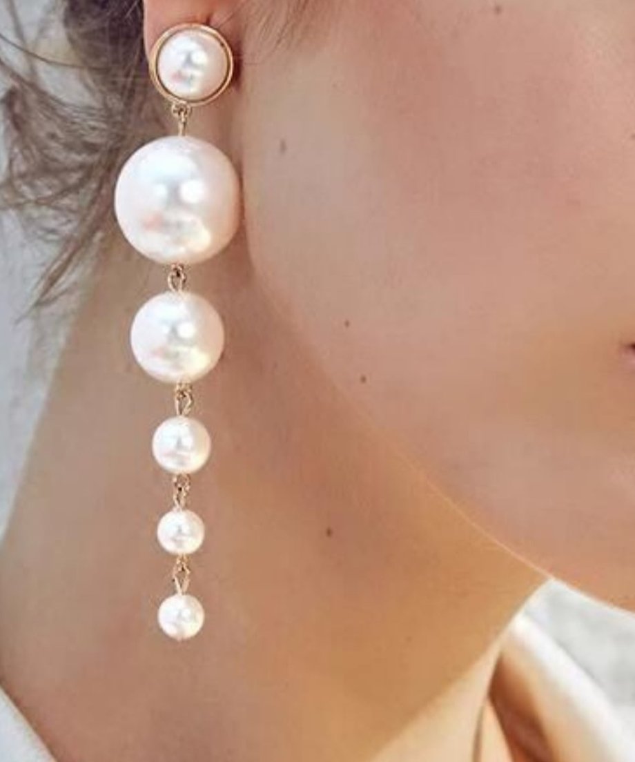 大小6粒のパールが連なったロングピアスを着用した女性の耳元のクローズアップ。パールの光沢とゴールドの金具が目立つ。