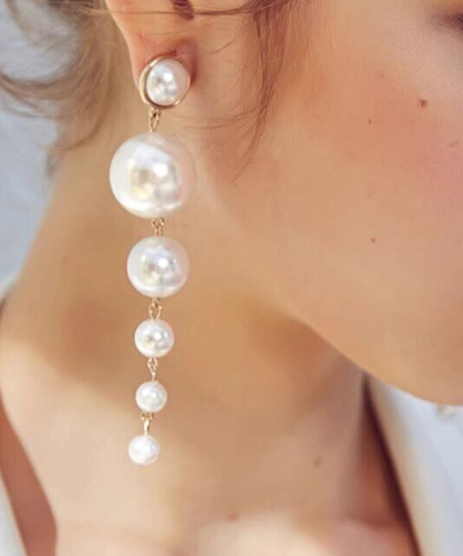 大粒から小粒へとグラデーションになったロングパールピアスを着用した女性の横顔。髪をアップにして、ピアスを強調したスタイル。