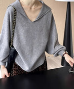 グレーのセーラーカラーVネックニットにレオパード柄のボトムスを合わせ、黒いチェーンバッグを肩にかけた女性のクローズアップ写真。