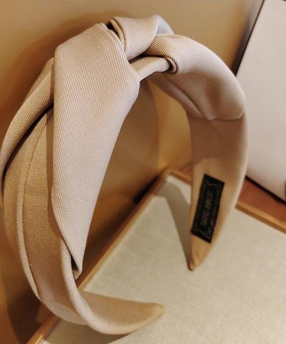 ベージュのノットデザインカチューシャを横からクローズアップした写真。裏側には「HAND MADE」のタグが付いている。