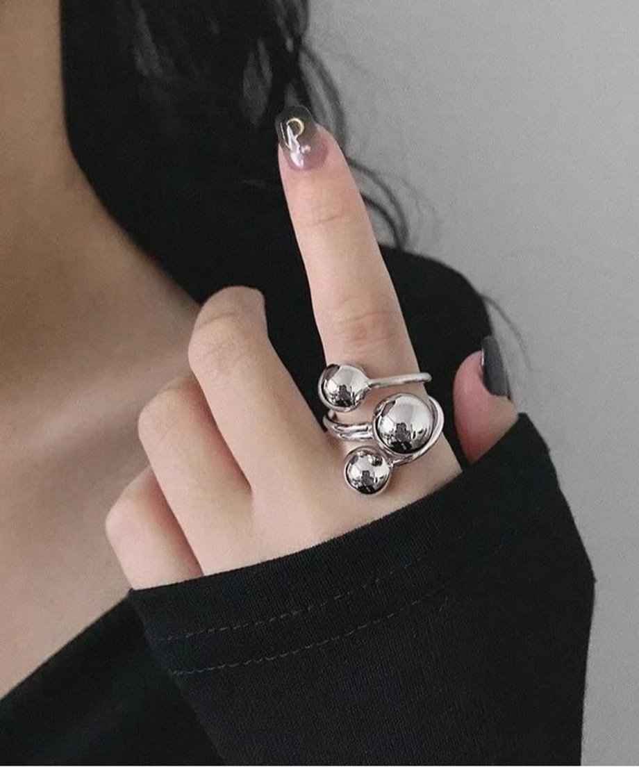 黒い長袖の上から、シルバーのスパイラルボールオープンリングを人差し指に着用した女性の手元のクローズアップ。