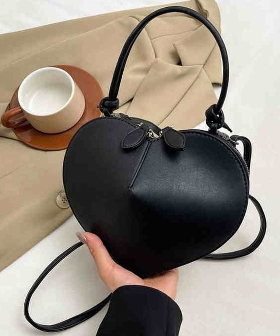 黒のマットなハート型ミニバッグを手に持っているクローズアップ画像。