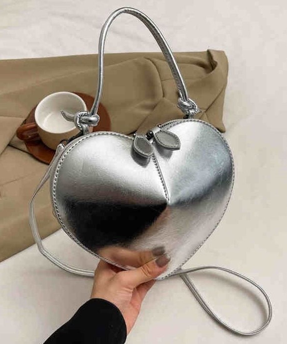 シルバーのマットなハート型ミニバッグを手に持っているクローズアップ画像。