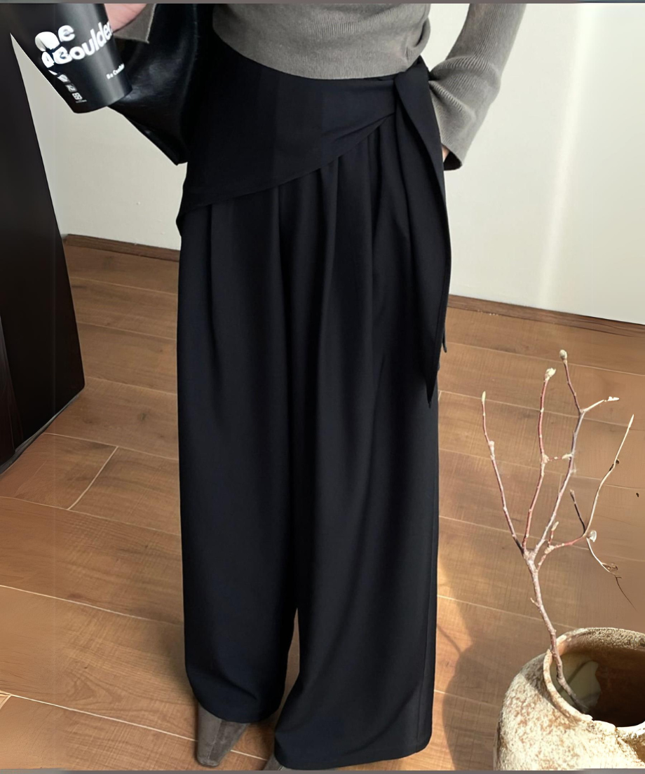 黒いワイドレッグパンツを着用した人物の立ち姿。スカーフ使いが印象的なウエストデザインが特徴的。