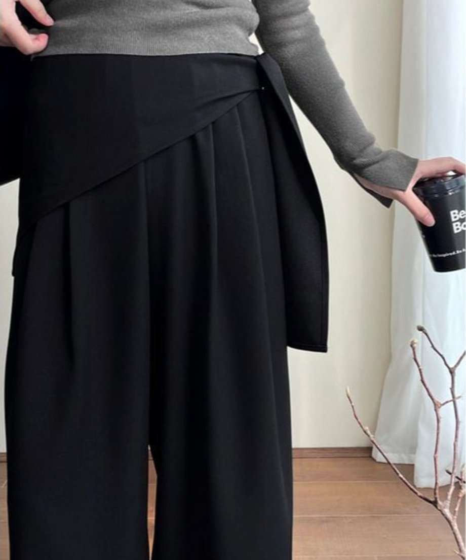 ブラックのワイドレッグパンツのウエスト部分のクローズアップ画像。ウエストにスカーフを巻いたデザインが印象的。