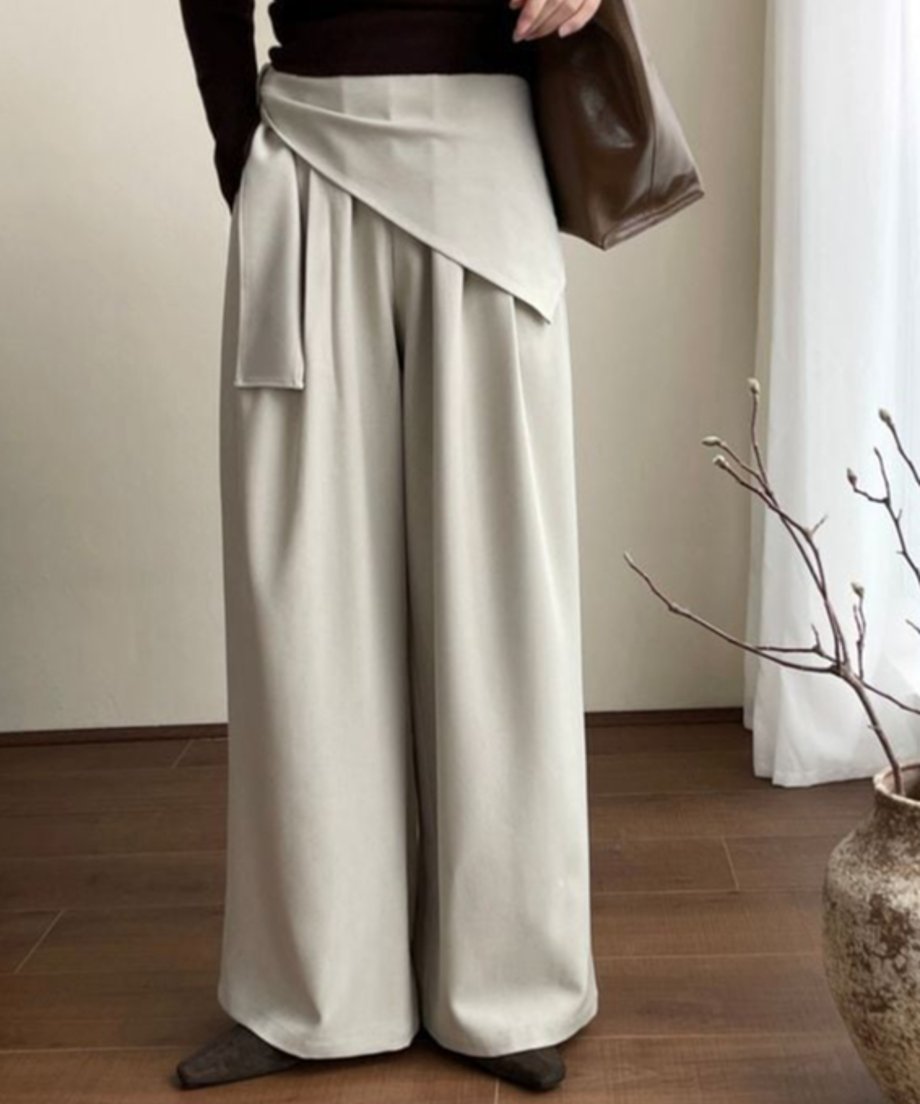 オフホワイトのワイドレッグパンツを着用した人物の立ち姿。スカーフを巻いたウエストデザインが見える。