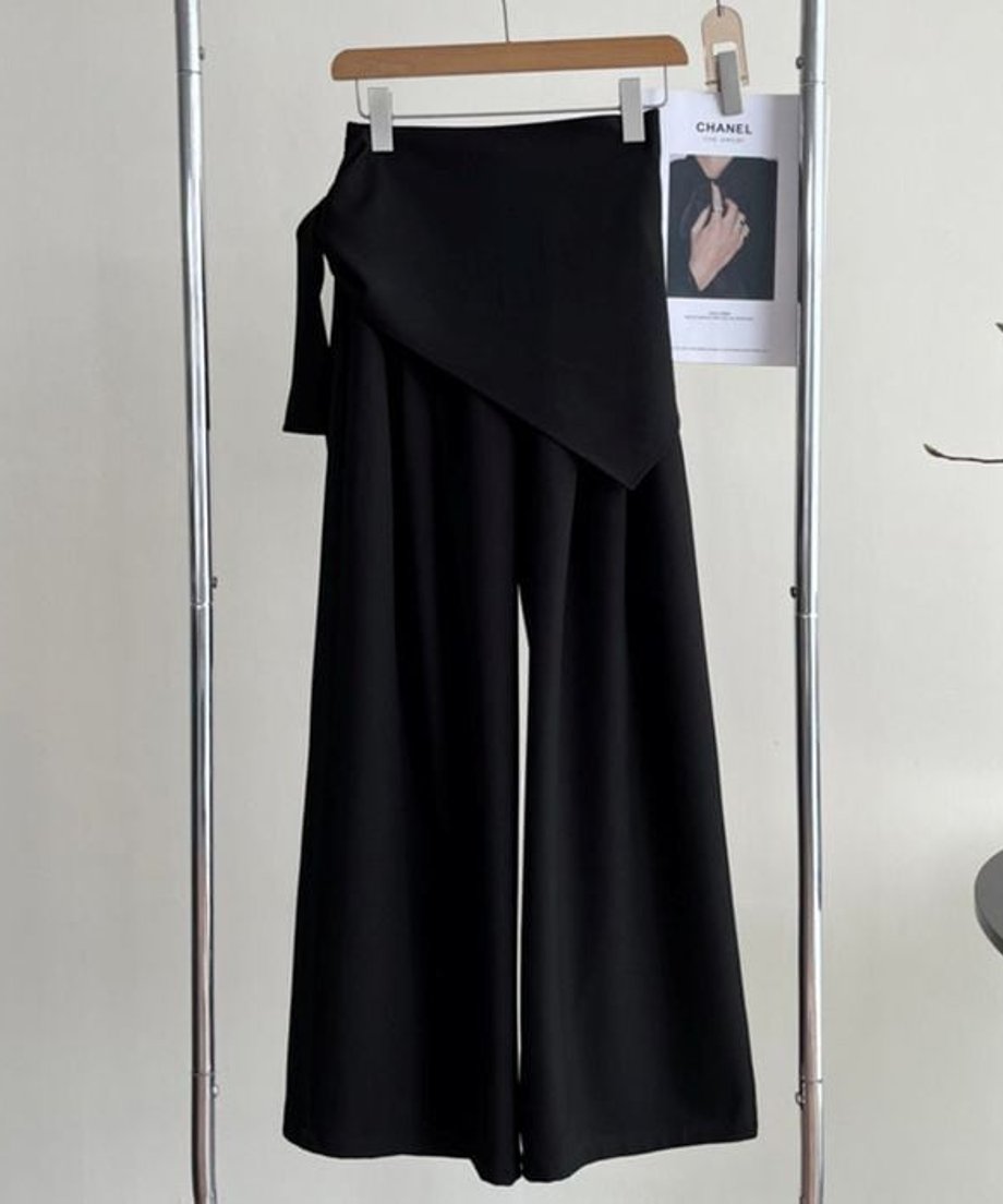 黒のワイドパンツがハンガーに掛けられた画像。ウエストには共布のスカーフが巻かれている。