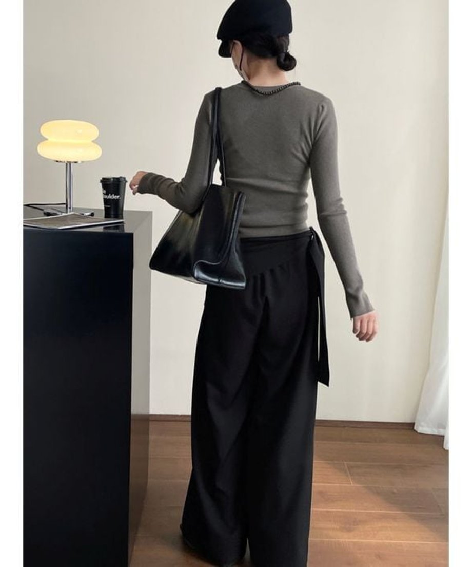 黒いワイドレッグパンツを着用し、後ろ姿を見せる人物。ベレー帽とトートバッグを合わせている。