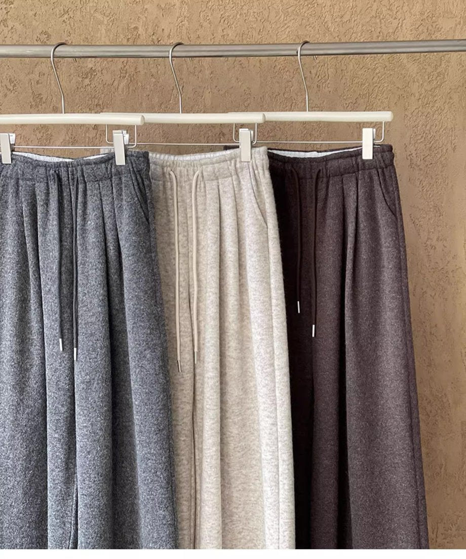 グレーとオフホワイトのワイドニットパンツがハンガーにかけられた状態で、素材の質感を示すクローズアップ。