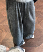グレーのワイドニットパンツとグレーのニットトップスを着用し、バッグを持った女性が鏡の前でポーズを取る膝下ショット。